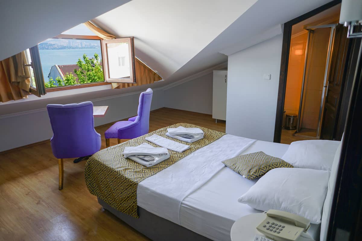 A hotel room with a bed, a chair, a desk, and a view of the outdoors.