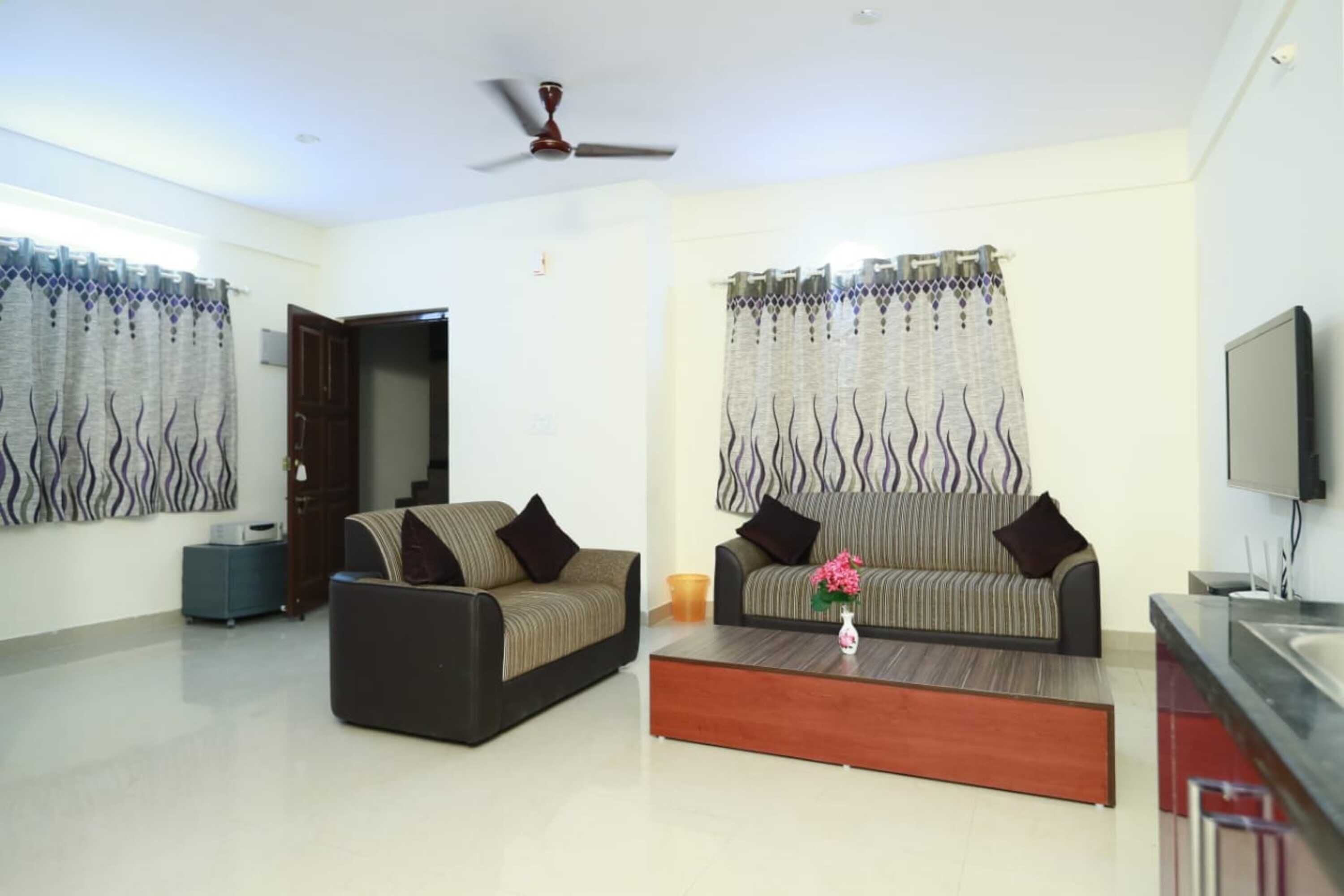 A living room with two sofas, a coffee table, a TV, and a ceiling fan.