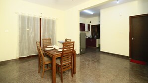 A dining area with a wooden table and chairs, a ceiling fan, and a kitchen in the background.