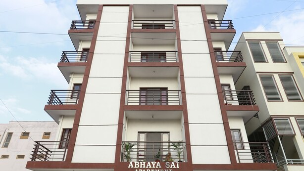 A multi-story apartment building with balconies and a sign that reads "ABHAYA SAI APARTMENT."