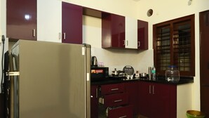 A kitchen with a refrigerator, cabinets, and a window.