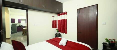 Une chambre d’hôtel avec un lit, une armoire, une porte et une vue sur le couloir.