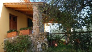 Un bâtiment en pierre doté d’un balcon en bois, d’une pergola en bois et d’une clôture rustique.