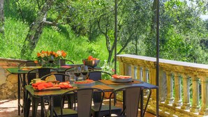 An outdoor dining area with a table set for two, surrounded by chairs, a yellow umbrella, and a view of lush greenery. - Villa / Independent home in Ponte A Moriano with 6 bedrooms sleeps 14 (Lucca)
