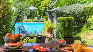 An outdoor dining area with a pool view, a table set with plates, glasses, and a bowl of fruit. - Villa / Independent home in Ponte A Moriano with 6 bedrooms sleeps 14 (Lucca)