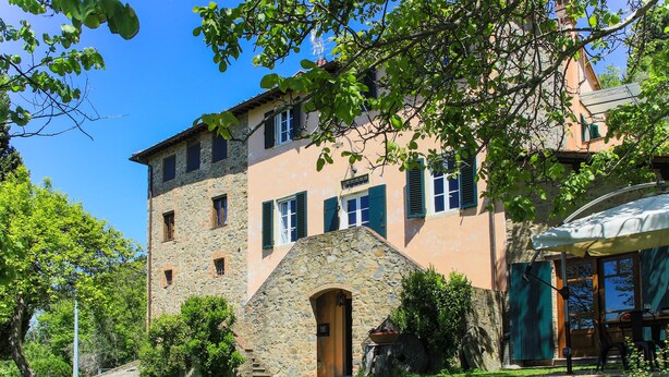 A stone building with a stone staircase leading to a wooden door, surrounded by lush greenery and a clear blue sky. - Villa / Independent home in Ponte A Moriano with 6 bedrooms sleeps 14 (Lucca)