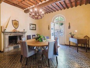 A dining area with a round table, chairs, a chandelier, a fireplace, and patterned floor tiles. - Villa / Independent home in Ponte A Moriano with 6 bedrooms sleeps 14 (Lucca)