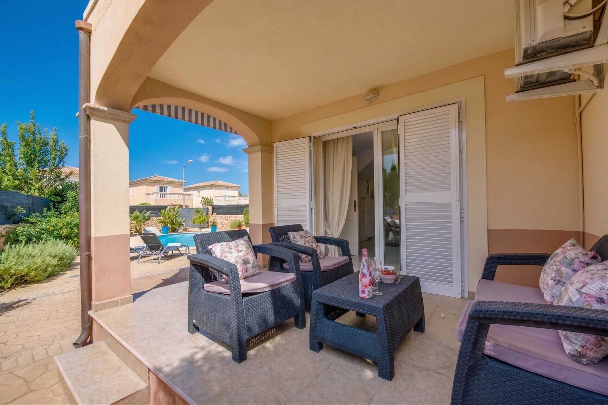 An outdoor patio with wicker furniture, a pool, and a view of neighboring houses.