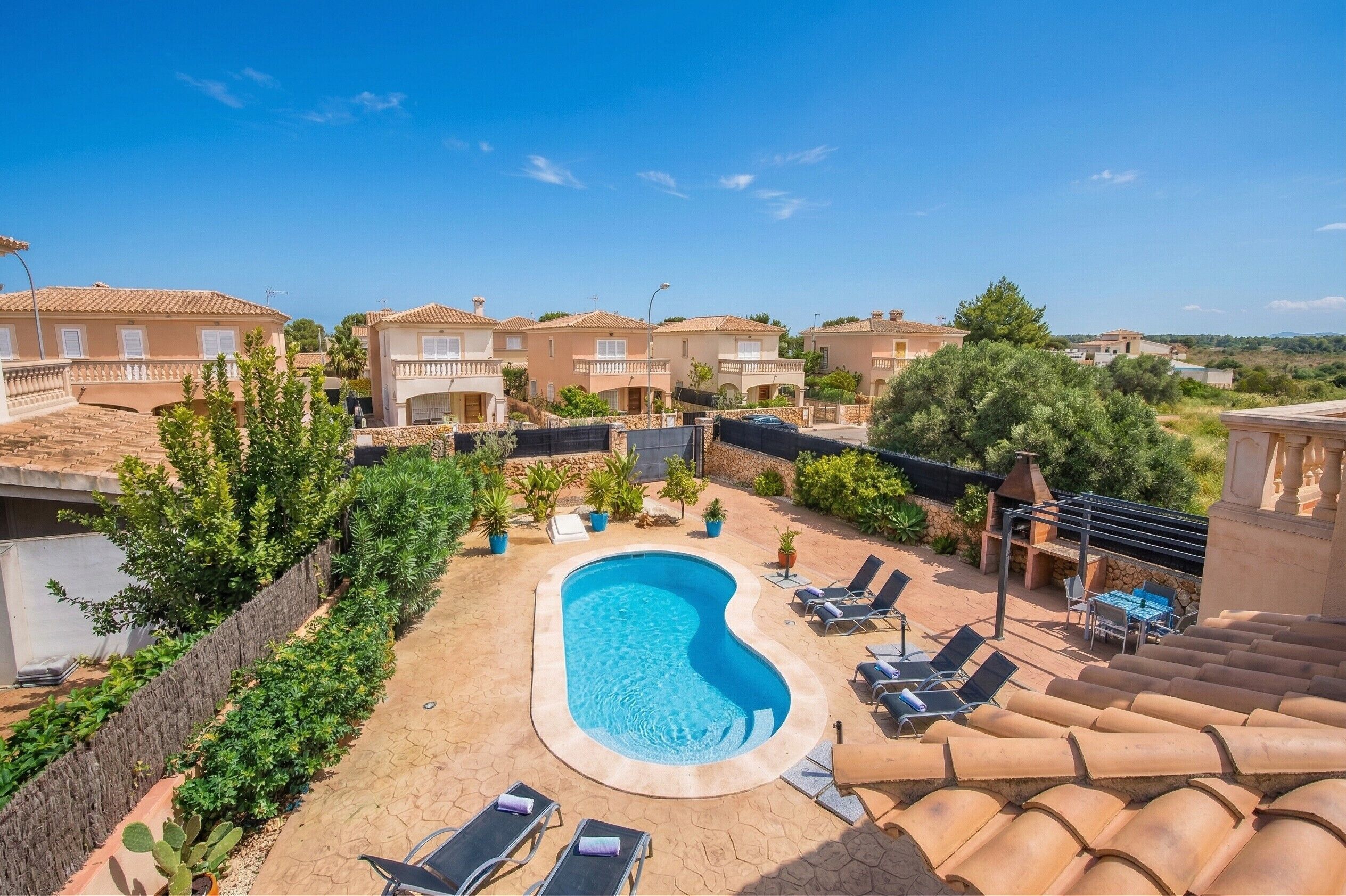 A swimming pool surrounded by lounge chairs, a stone wall, and greenery.