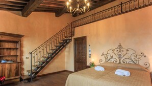 Une chambre à coucher avec un escalier en bois, un lit avec une tête de lit et une table de chevet avec une lampe.