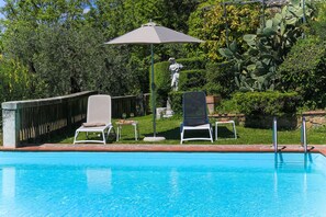 Une piscine avec deux chaises longues et une statue.