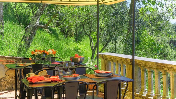 Un espace de restauration en plein air avec une table dressée pour deux personnes, entouré d’une végétation luxuriante.