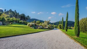 A gravel path leading through a well-maintained garden with various shrubs and trees, bordered by a stone wall. - Villa / Independent home in Lucca with 3 bedrooms sleeps 6 (Lucca)