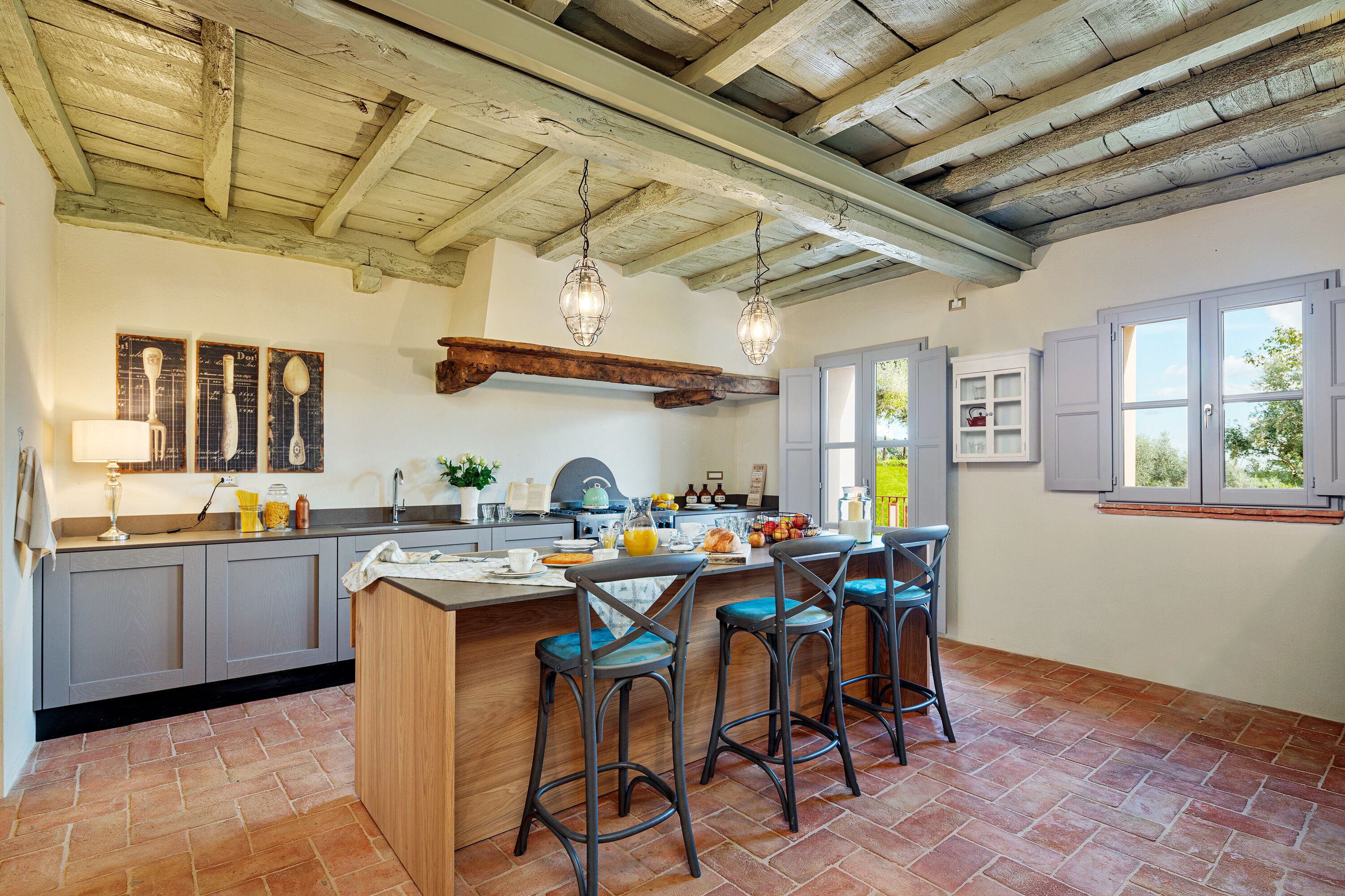 A kitchen with a wooden island, bar stools, and hanging pendant lights.