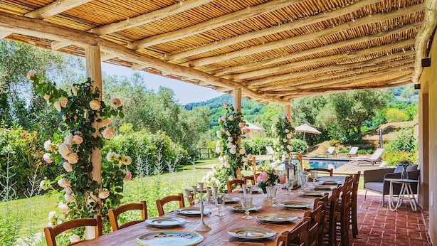 An outdoor dining area with a long wooden table set for a meal, surrounded by chairs, with a view of a pool and greenery in the background. - Villa / Independent home in Lucca with 5 bedrooms sleeps 10 (Lucca)