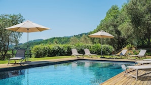 A rectangular swimming pool with clear blue water, surrounded by wooden decking. There are lounge chairs and umbrellas around the pool. - Villa / Independent home in Lucca with 5 bedrooms sleeps 10 (Lucca)