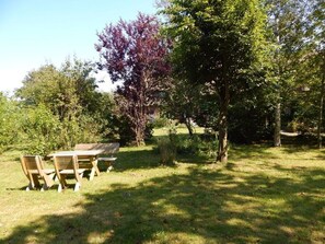 A picnic table with chairs in a grassy area surrounded by trees. - Old school goting, classroom (Nieblum)