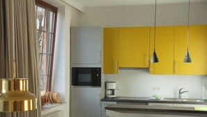 A modern kitchen with yellow cabinets, a built-in microwave, and a coffee maker. - Old school goting, classroom (Nieblum)
