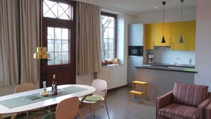 A compact living space with a dining area, a kitchenette, and a seating area. - Old school goting, classroom (Nieblum)