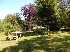 A picnic table with chairs in a grassy area surrounded by trees.