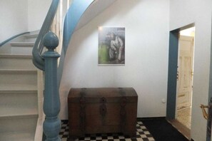 A staircase with a blue handrail, a wooden chest, and a framed picture on the wall. - Old school Goting, southern class (Nieblum)