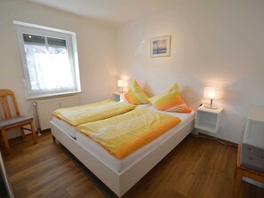 Une chambre à coucher avec un lit, deux lampes de chevet, une chaise, une fenêtre et un tableau au mur.