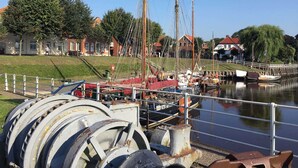 A marina with boats docked, a grassy area, and buildings in the background.
