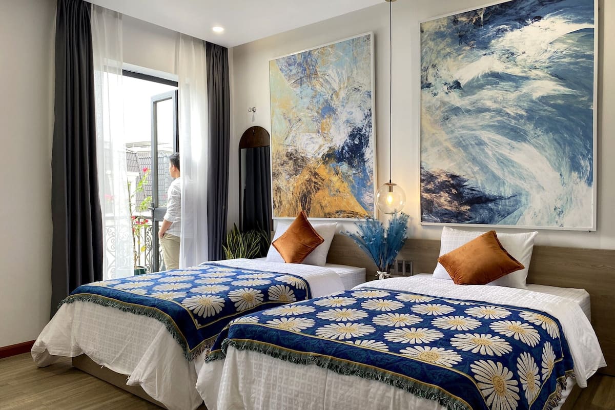 Een hotelkamer met twee bedden, een groot abstract schilderij en uitzicht op het exterieur.