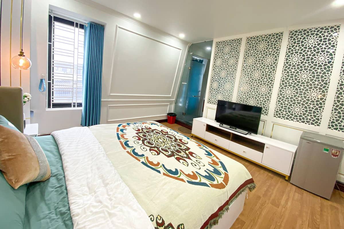 Een slaapkamer met een bed, een televisie, een kledingkast en een decoratief paneel aan de muur.