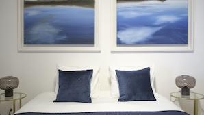 Una camera da letto con un letto, due cuscini, un comodino con una lampada e due quadri appesi al muro.