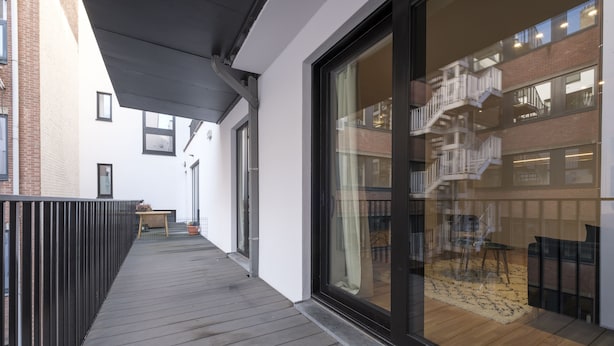 Un pontile in legno con una porta vetrata che dà su un interno a più livelli con una scala.