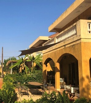 A building with a balcony, outdoor seating area, and greenery.