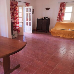 Una habitación con una mesa de madera, un sofá, un armario y una puerta.