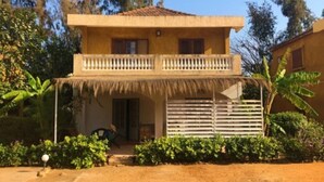 A two-story building with a balcony, a thatched roof, and a gate. - Villa watermelon Ngaparou 1 (Ngaparou)