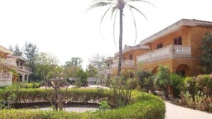 A courtyard with a palm tree, a small pond, and buildings with balconies. - Villa watermelon Ngaparou 1 (Ngaparou)