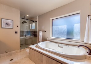 Een moderne badkamer met een groot bad, een douchecabine van glas en een groot raam voor natuurlijk licht.