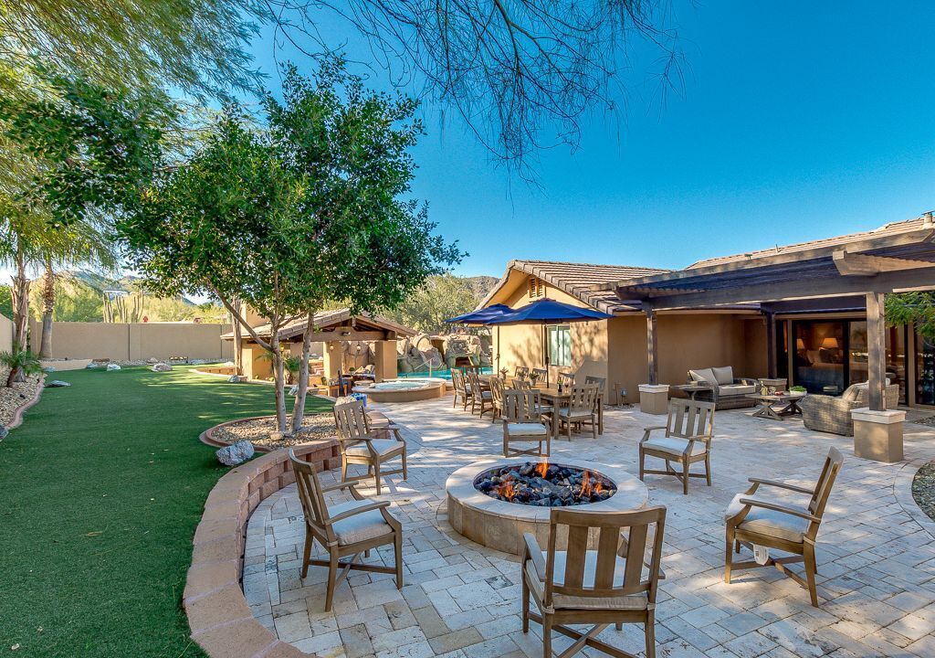 An outdoor patio area with seating, a fire pit, and a pool.