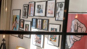 Una pared con varios cuadros enmarcados, un sofá y una lámpara de pie.