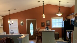 A spacious living room with a brown couch, a dining area with a table and chairs, and a kitchen with appliances and cabinets. - The cottage of lake seminole (Donalsonville)