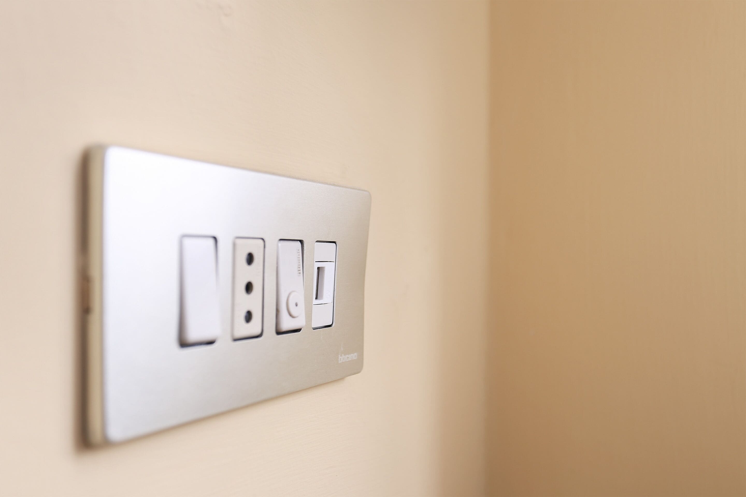 A wall-mounted electrical outlet with three switches and a USB port.