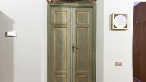 Una porta doppia chiusa con una semplice maniglia, un interruttore della luce e un quadro appeso al muro.