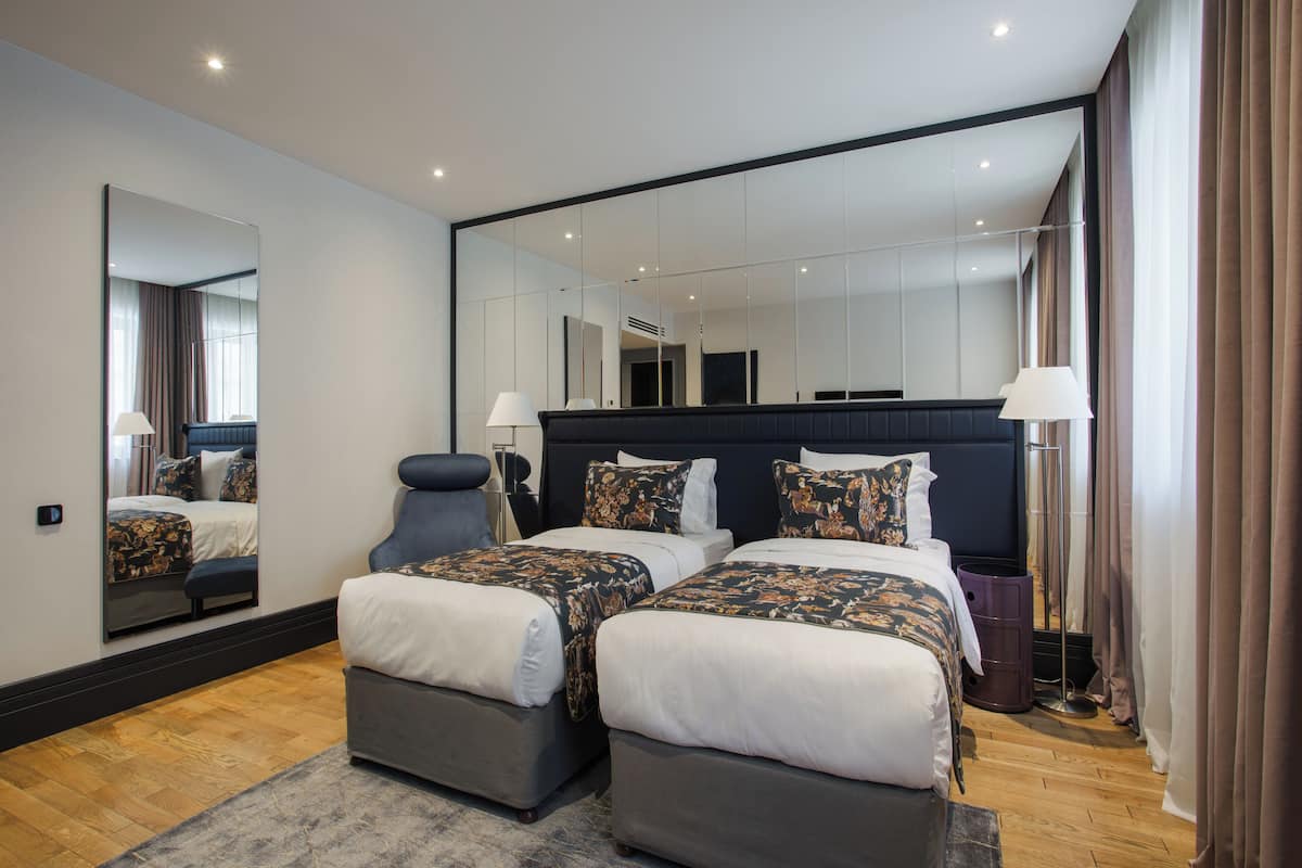 Een moderne hotelkamer met twee bedden, een grote spiegel en uitzicht op de stad.