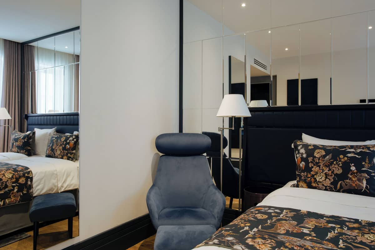 Een hotelkamer met twee bedden, een stoel, een bureau en een grote spiegel.