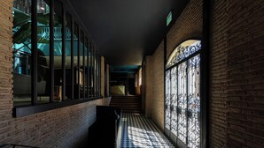 A corridor with a checkered floor, brick walls, and large windows with metal grilles. - Boutique Hotel Puris Moedani (Tbilisi)