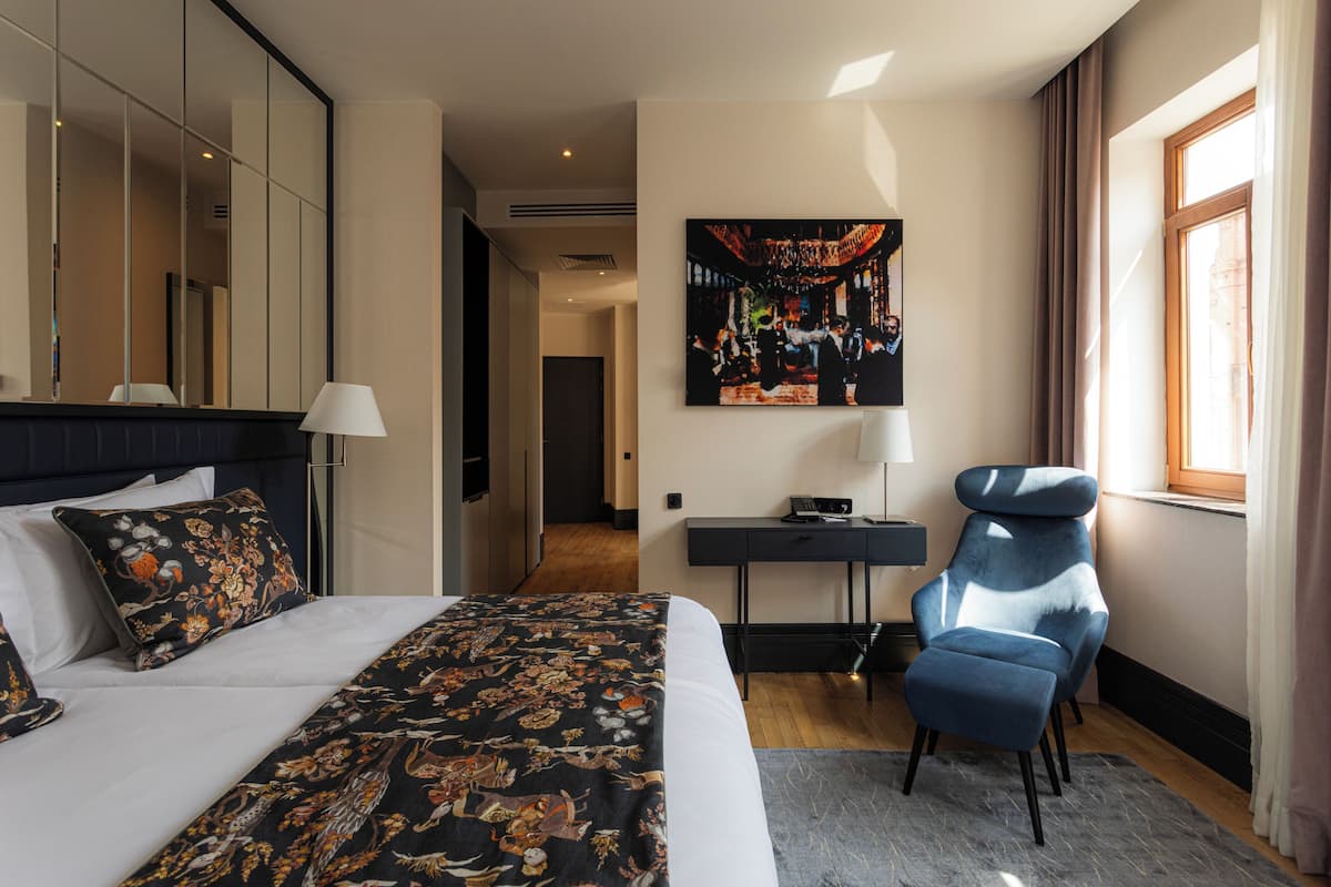 Een hotelkamer met een groot bed, een bureau, een stoel en een schilderij aan de muur.