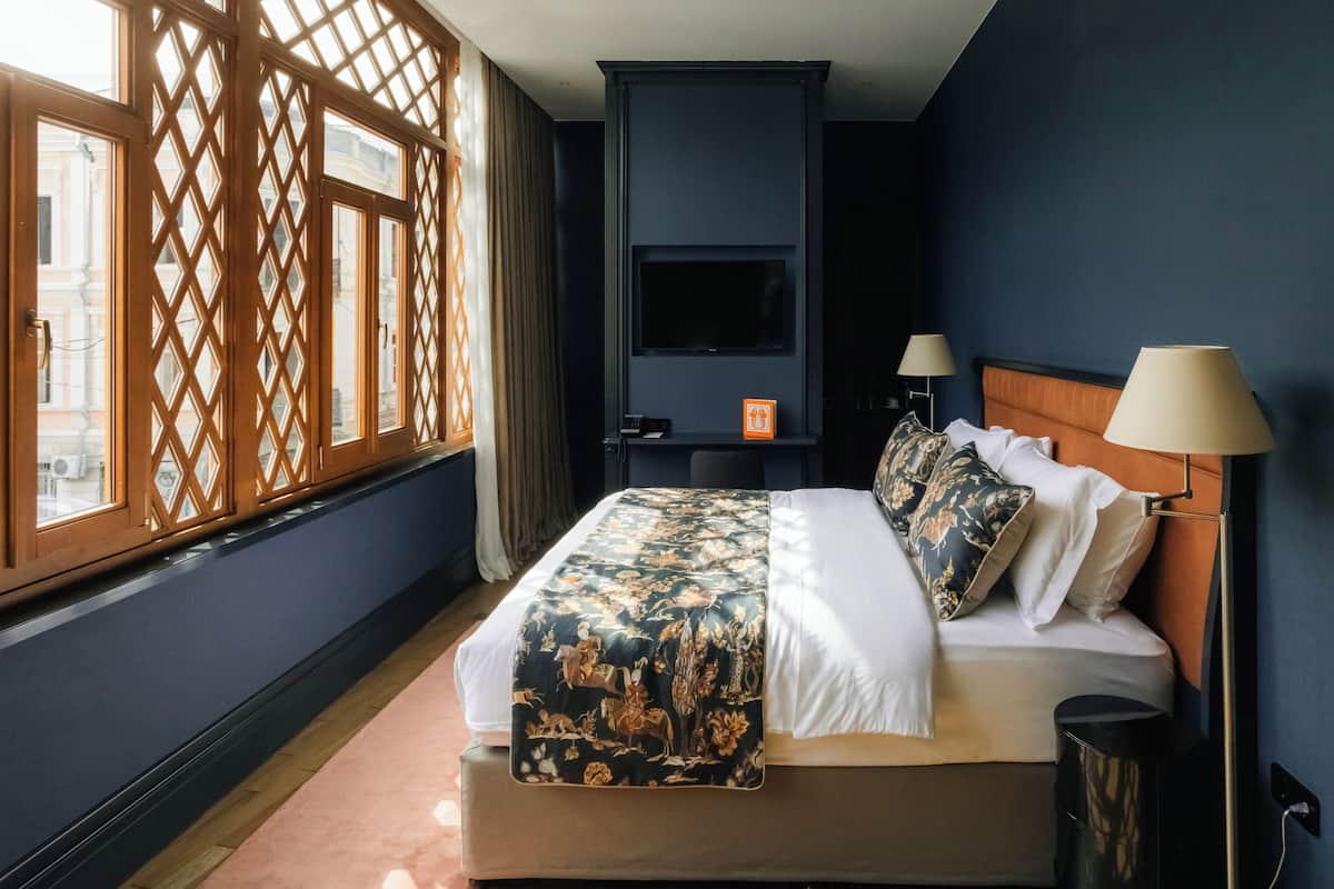 Een hotelkamer met een bed, een televisie, een bureau en een raam met uitzicht op gebouwen.