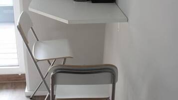 A corner room with a white desk, a black coffee maker, and a white chair.