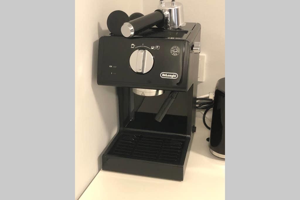 A De'Longhi espresso machine with a drip tray, control panel, and steam wand.