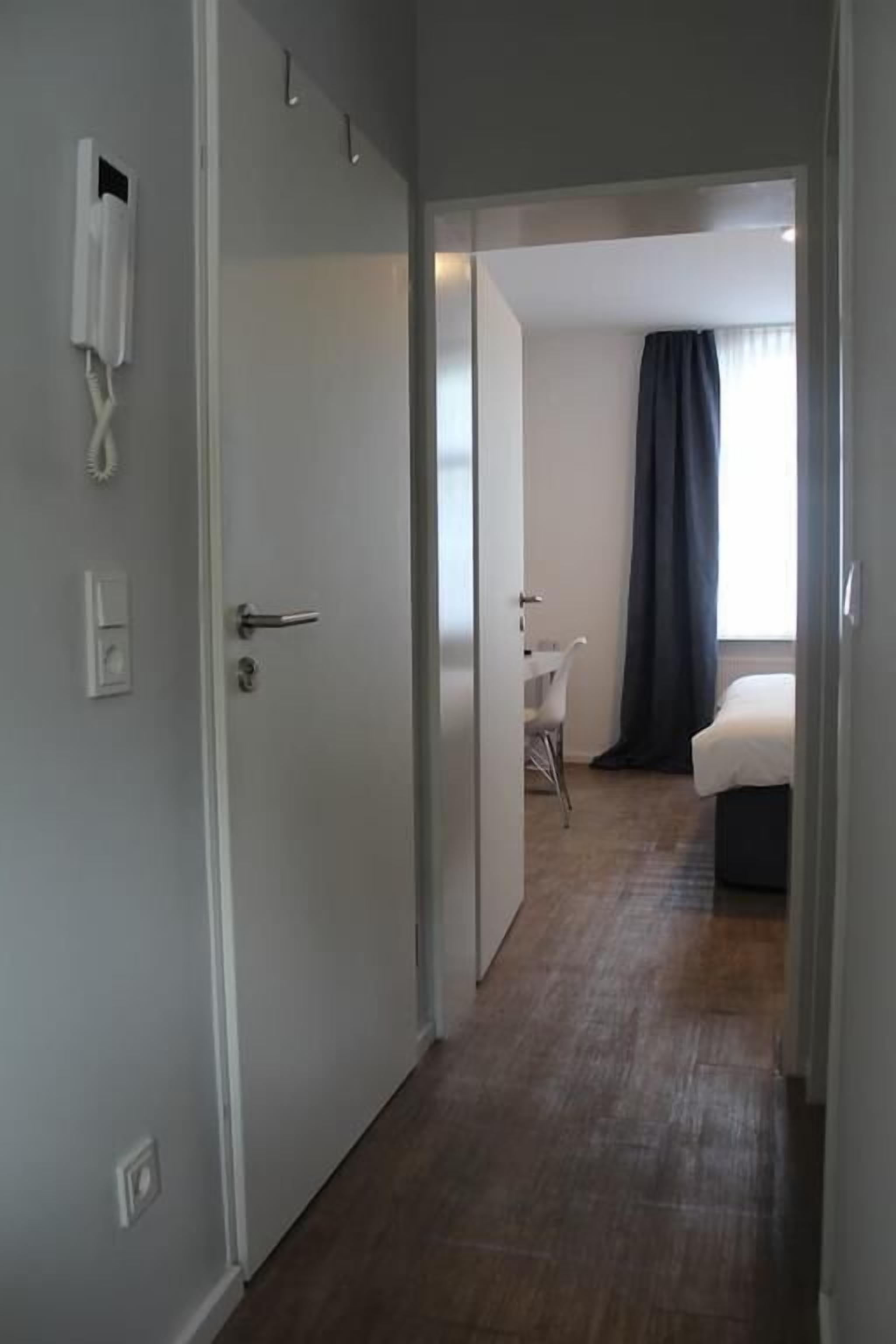 Ett hotellrum med trägolv, en säng, ett skrivbord och en stol.