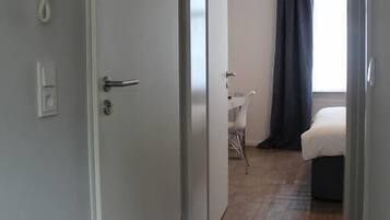 Ett hotellrum med trägolv, en säng, ett skrivbord och en stol.